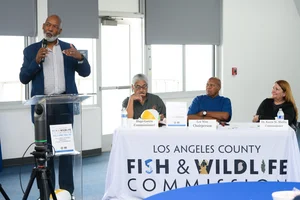 A group of people sitting at tables at an even while a man speaks to them.