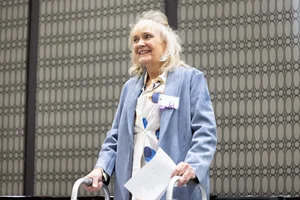 a woman smiling and holding a piece of paper.