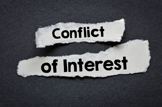 Two torn pieces of white paper placed on a dark textured background with bold black text that reads Conflict on the top piece and of Interest on the bottom piece.