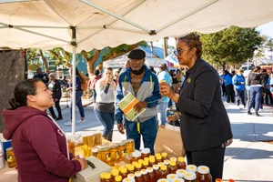 Supervisor Mitchell speaking with a vendor at a honey stand
