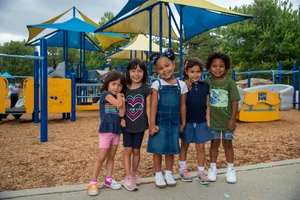 5 children standing in front of a playground