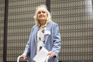 a woman smiling and holding a piece of paper.