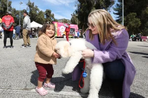 Supervisor Horvath holding a dog for a young girl to pet