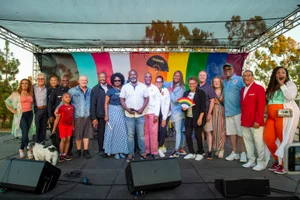Supervisor Mitchell group photo in front of rainbow colored flag