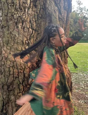 Young woman posing in front of a tree.