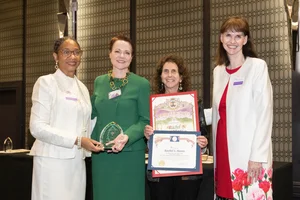 a group of women smiling and holding up a few awards.