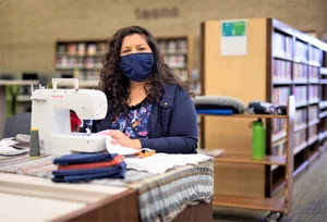 A woman knitting fabric at a table.