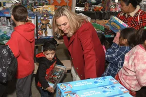 Supervisor Barger in a group photo with young children grabbing toys