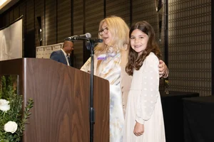 a women speaking at the podium with a young girl next to her.