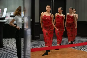 4 women posing in red dresses looking at another woman.