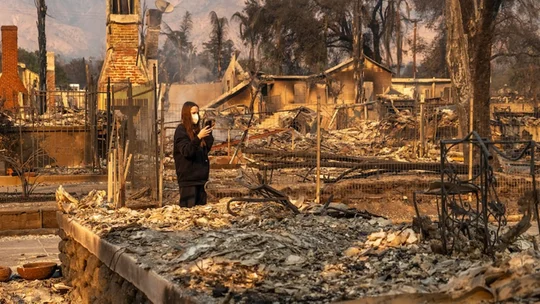 Woman standing in the city after buildings have been burnt down.