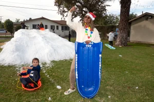 Supervisor Mitchell posing with young child in front of snow hill with snow sleds