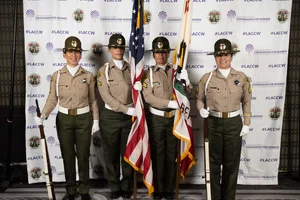 4 county officers posing with flags and rifles for a photo.