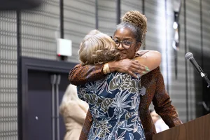 Supervisor Mitchell hugging someone at a podium.