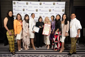a group of people smiling while they hold up a few awards.