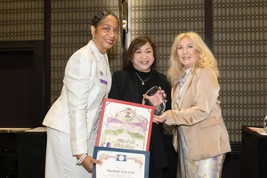 3 women smiling and holding up a few awards.