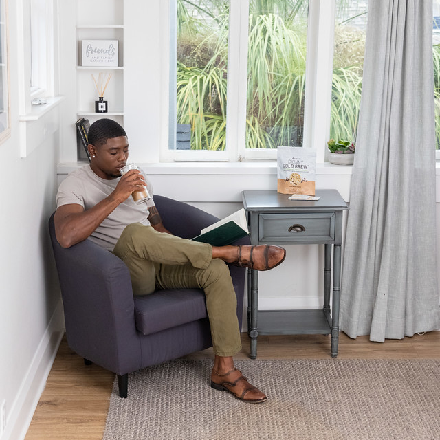 A man sitting in a chair drinking a book