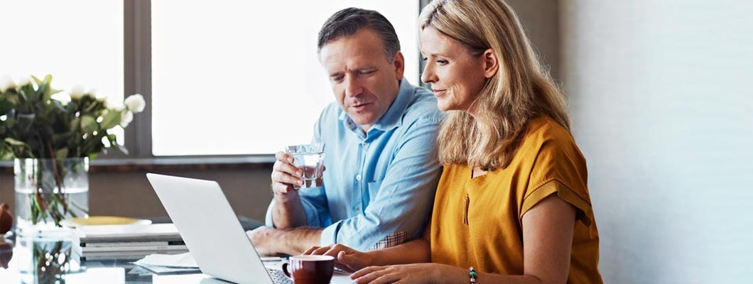 Mature couple paying their bills online from home. Find Indexed annuities.