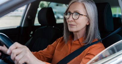Senior woman driving new car. How to Buy a Car If You're Upside Down on Your Loan.