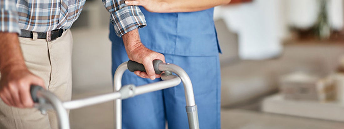 Woman assisting her elderly patient who's using a walker for support. Traditional long term care insurance cost.