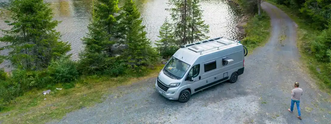 Man walks towards his van parked by the lake. Find Class B Camper Van Insurance. 
