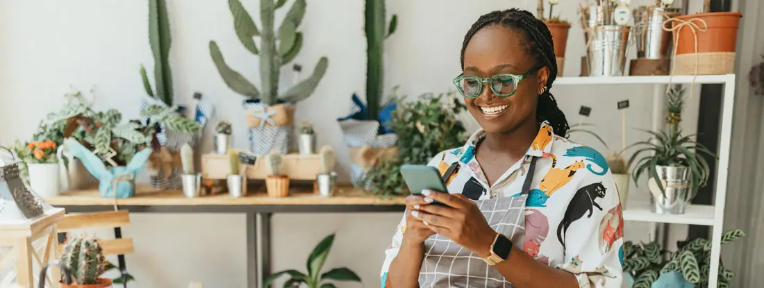 Young woman using mobile phone in the shop. Understanding Small Business Insurance Requirements in 2026.