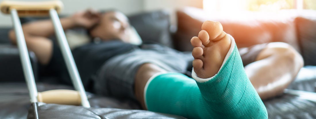 Male patient with splint cast and crutches during surgery rehabilitation.  Find Group short term disability insurance.