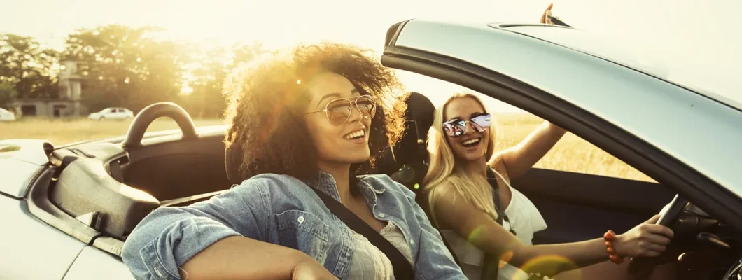 Young adults traveling in car and having fun. How auto insurance works for family members.