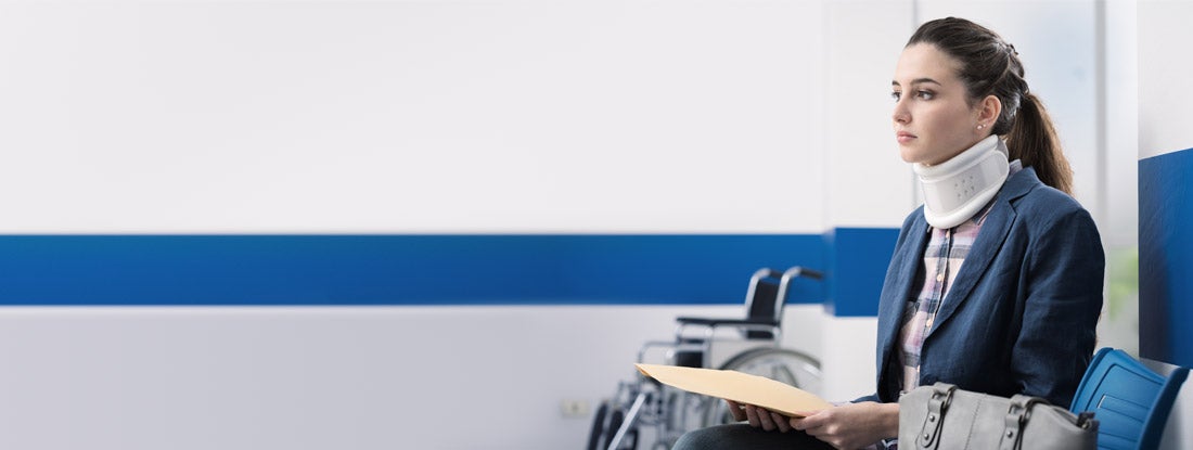 Woman in a collar sitting in a waiting room after filing an insurance claim or a personal injury lawsuit. Disability insurance waiver of premium.
