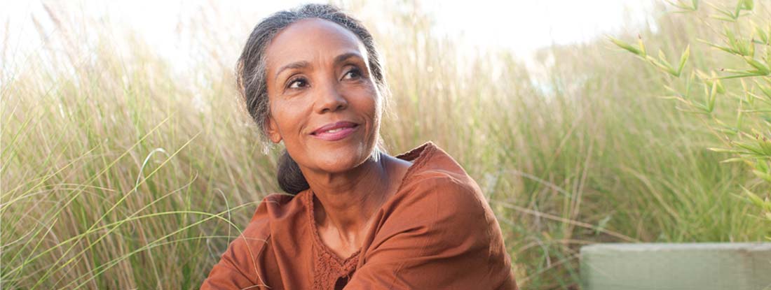 Serene woman sitting in sunny field. Advantages and disadvantages of variable annuities.