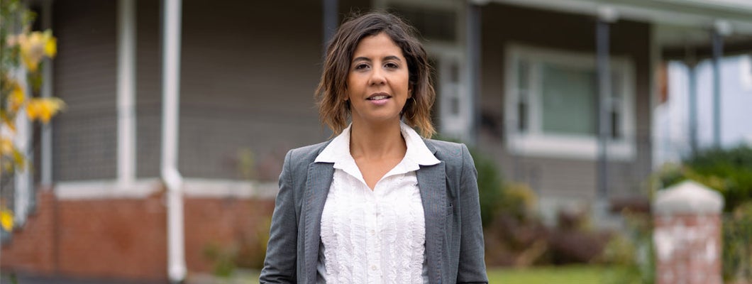 Female landlord in front of a house. Find Kansas landlord insurance.