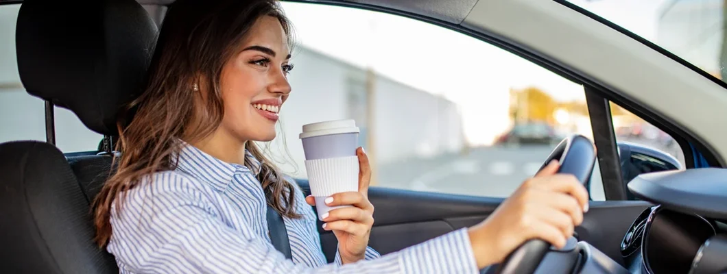 Woman with coffee to go driving her car. How to Find the Best Car Insurance in Brookfield, WI. 