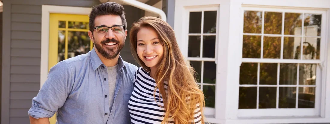 Couple Standing Outside New Home. 8 Tips When Purchasing a Home For Sale By Owner.