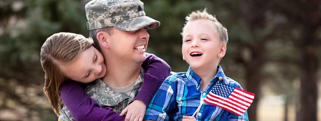 Military service member in uniform sharing a happy moment with two young children. Military and veteran life insurance discounts.