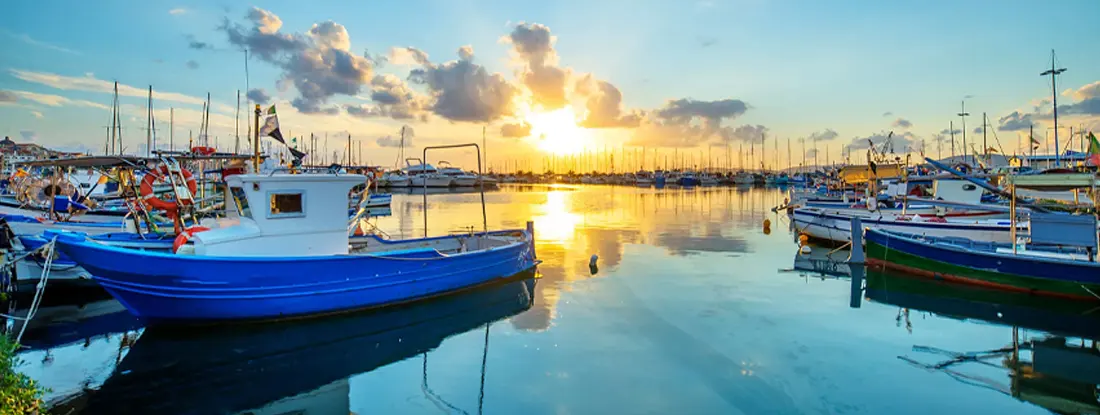 A sunset over lake with a port in the background. Find Ohio Boat Insurance.