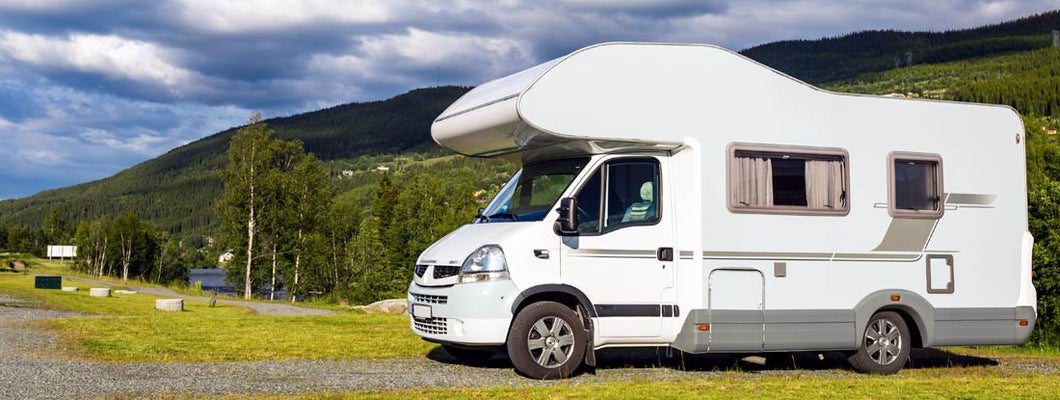 Modern white RV at camping site in beautiful New Hampshire. Find New Hampshire RV Insurance.