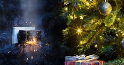 Christmas lights plugged in at night with sparks from outlet. Holiday Decoration Hazards.