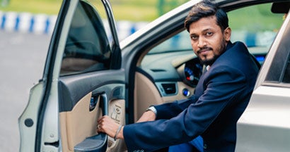 Young man opening car door while sitting in the car. What is a car insurance premium?