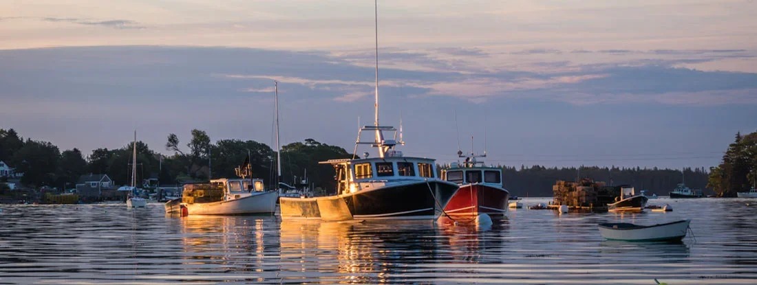 Lobster boats in the quiet and still harbor at dawn on a summer morning. Find Massachusetts Boat Insurance.
