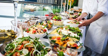 Caterer serving a large buffet table full of delicious food. Find Catering Insurance.