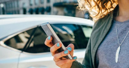 Woman using smart phone standing on street. My Insurance Rates in West Virginia Went Up! What Should I Do?