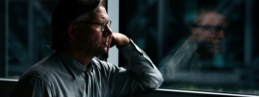 Man looking out window in despair. Suicide Life Insurance.