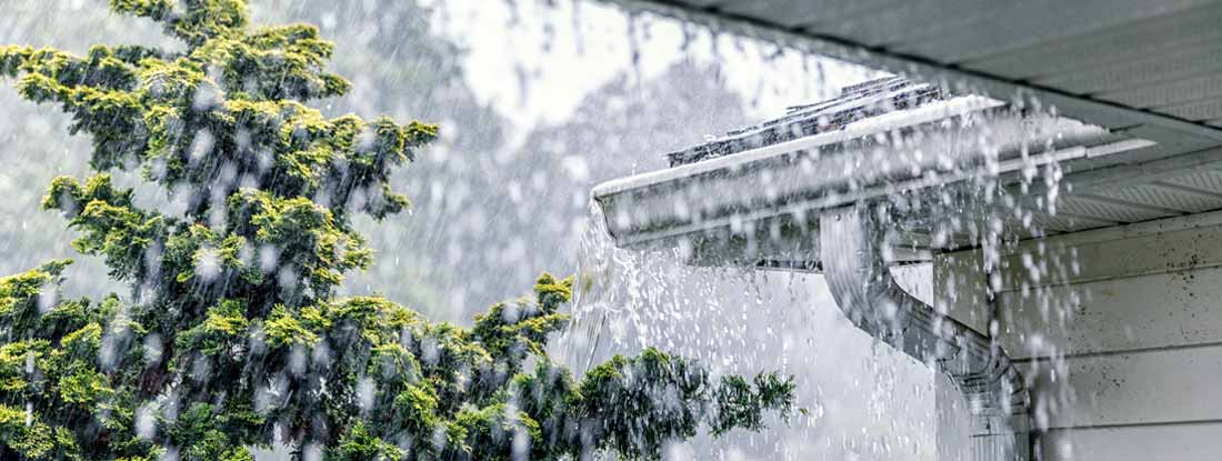 Downpour rain water overflowing over the overhanging eaves of gutter system. Gutter Floods.