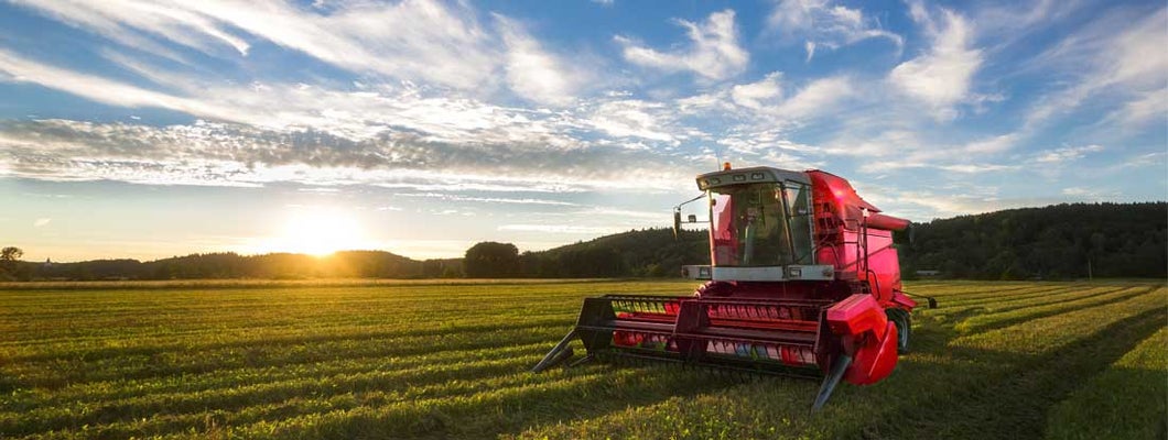 Big red combine harvester in sunset light. How to Insure Farm Equipment.