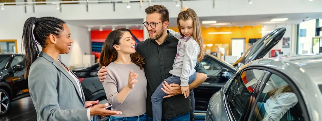 Saleswoman at car dealership center helping family lease a new vehicle. Guide to Leasing a Car.