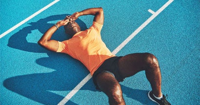 Exhausted young athletic lying on a running track after training