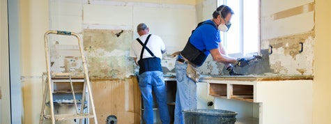 Two men tearing out old kitchen during home renovations. How Much Does It Cost to Demolish a House?