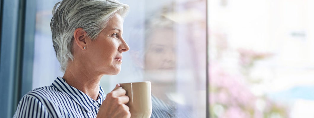  Mature businesswoman drinking coffee while looking out of her office window.  Find Retirement Annuities.