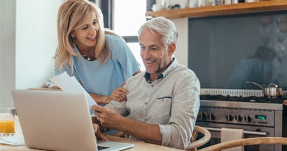 Mature couple smiling while calculating annuity interest rates together. Annuity Interest Rates.