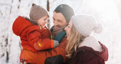 young family, being playful outdoors in nature covered in snow